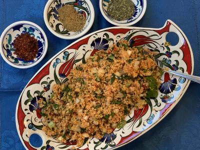 Kisir (bulgur salad) in serving dish with spices on the table