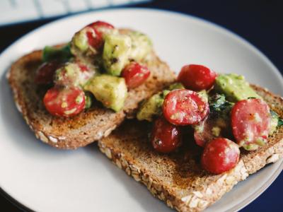 Two pieces of whole grain toast with tomatoes and avocados