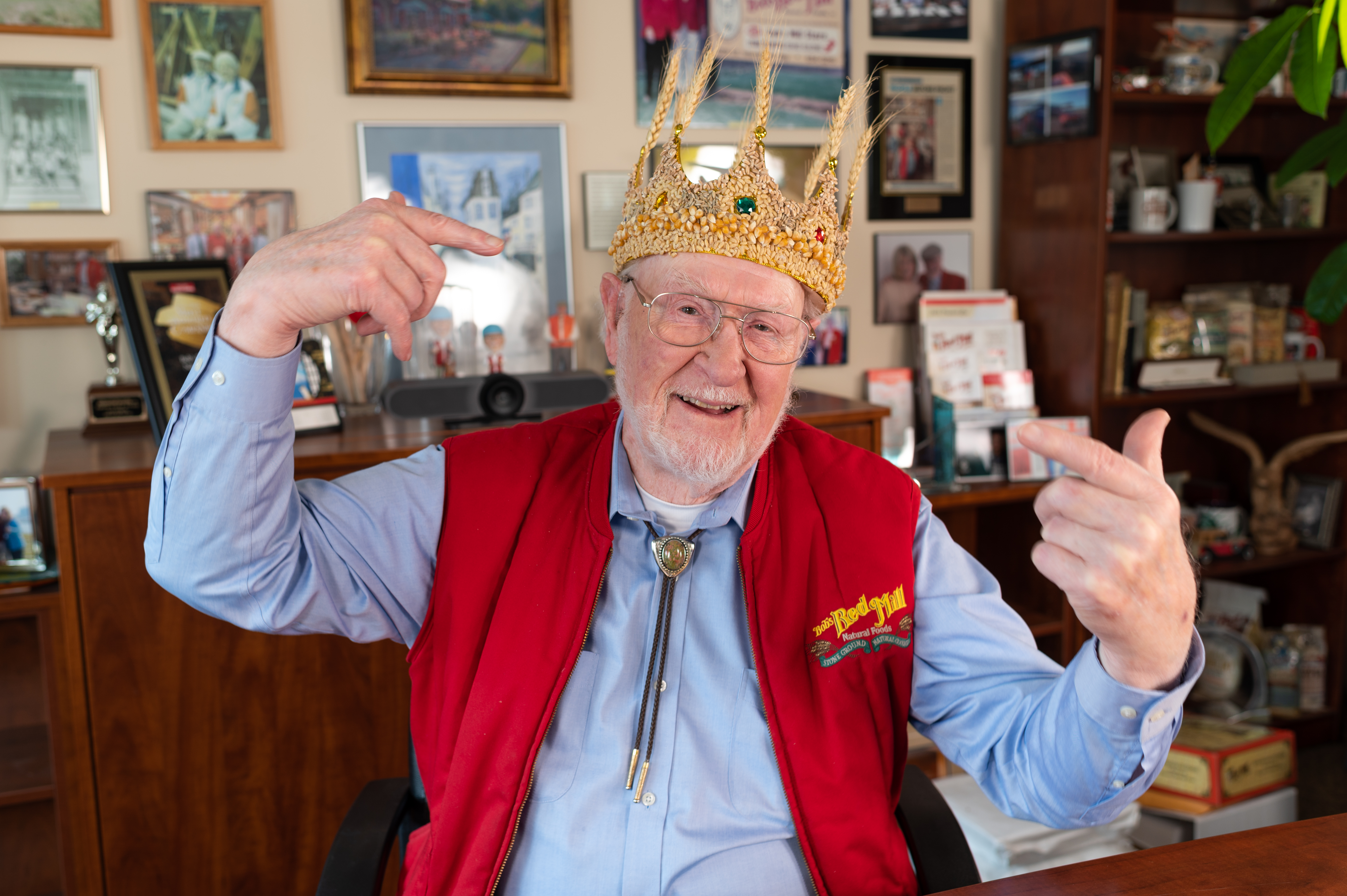 Bob Moore wearing the Whole Grain Crown, a large crown covered in grains of corn, wheat, etc. He is gesturing excitedly at the crown.