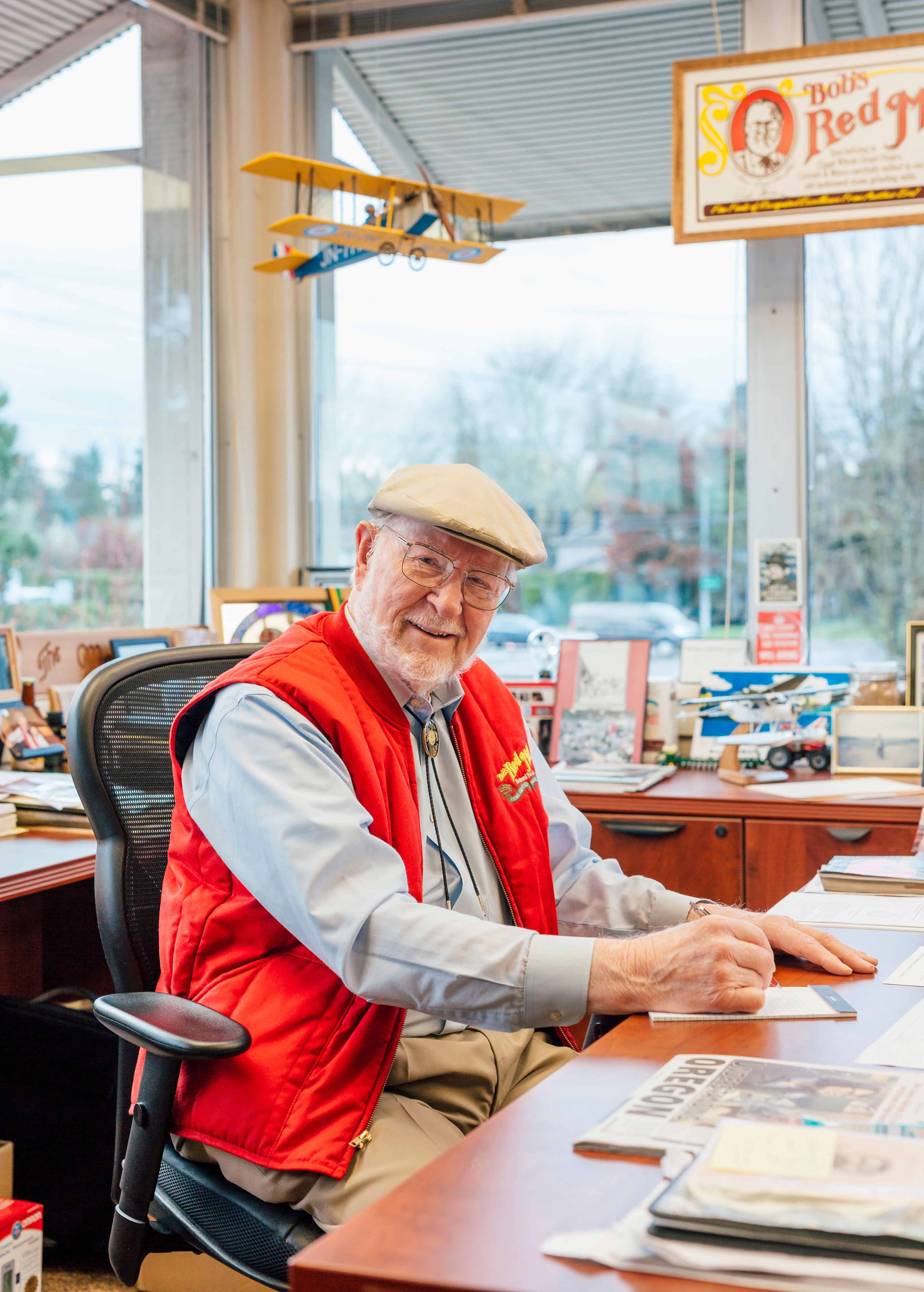 Bob Moore, sitting at his desk and smiling. Above his head is a model airplane.