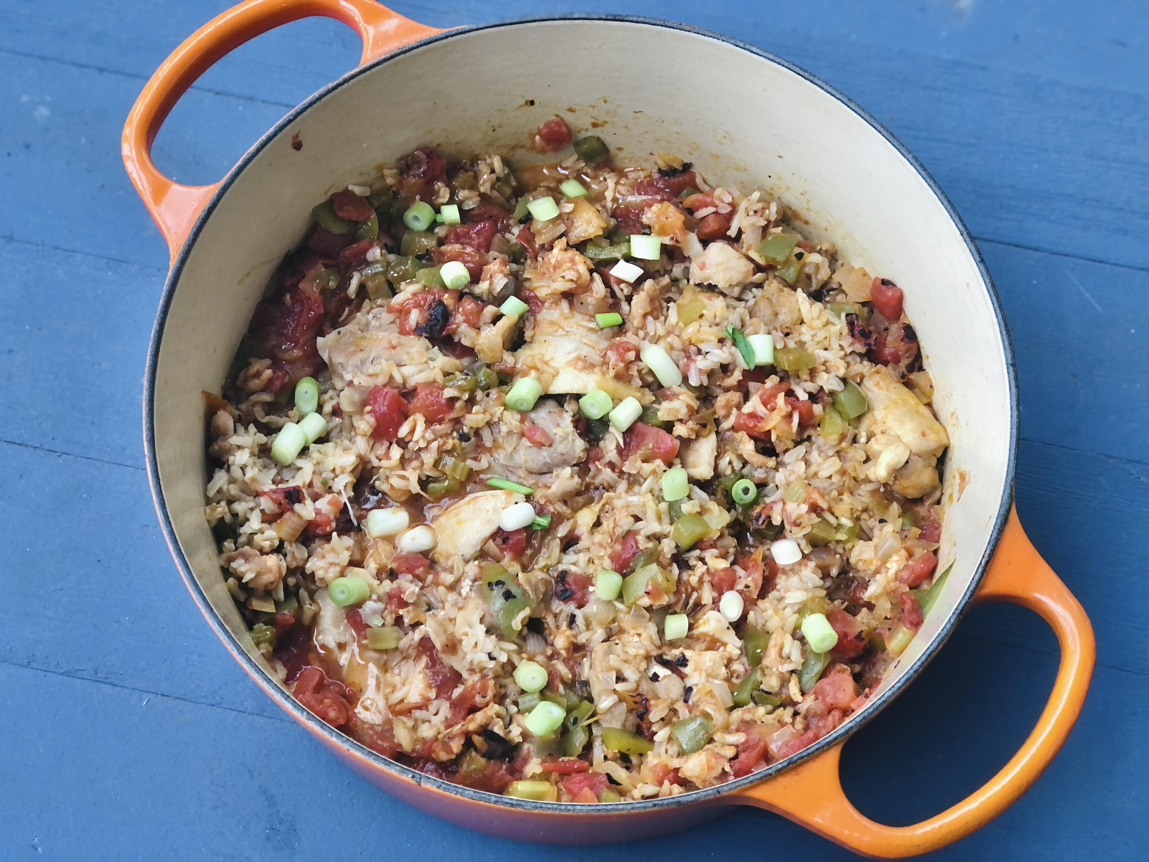 vegetable and chicken jambalaya in an orange pot on a blue background