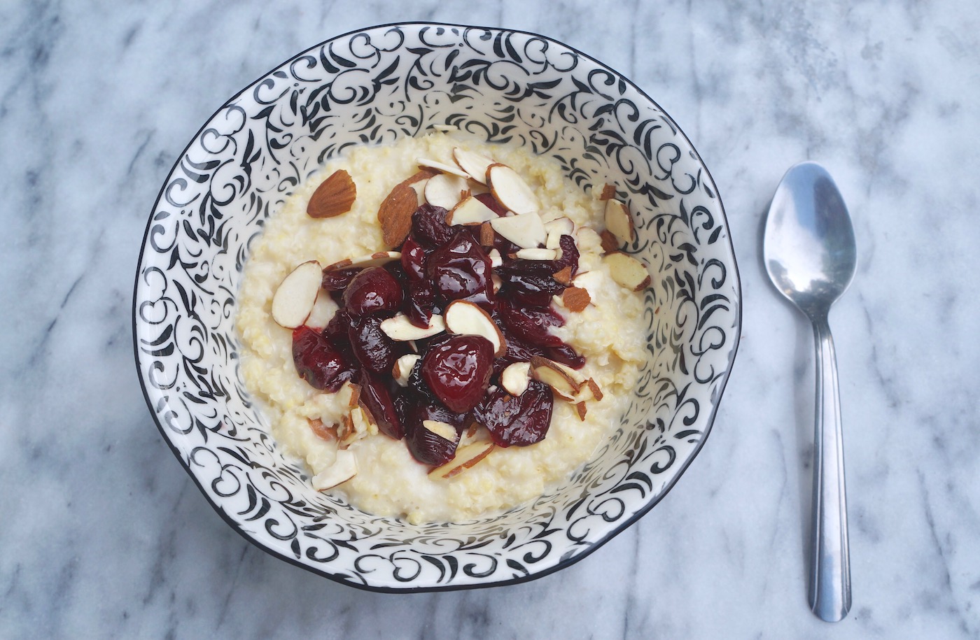 Millet porridge topped with cherry compote and almonds