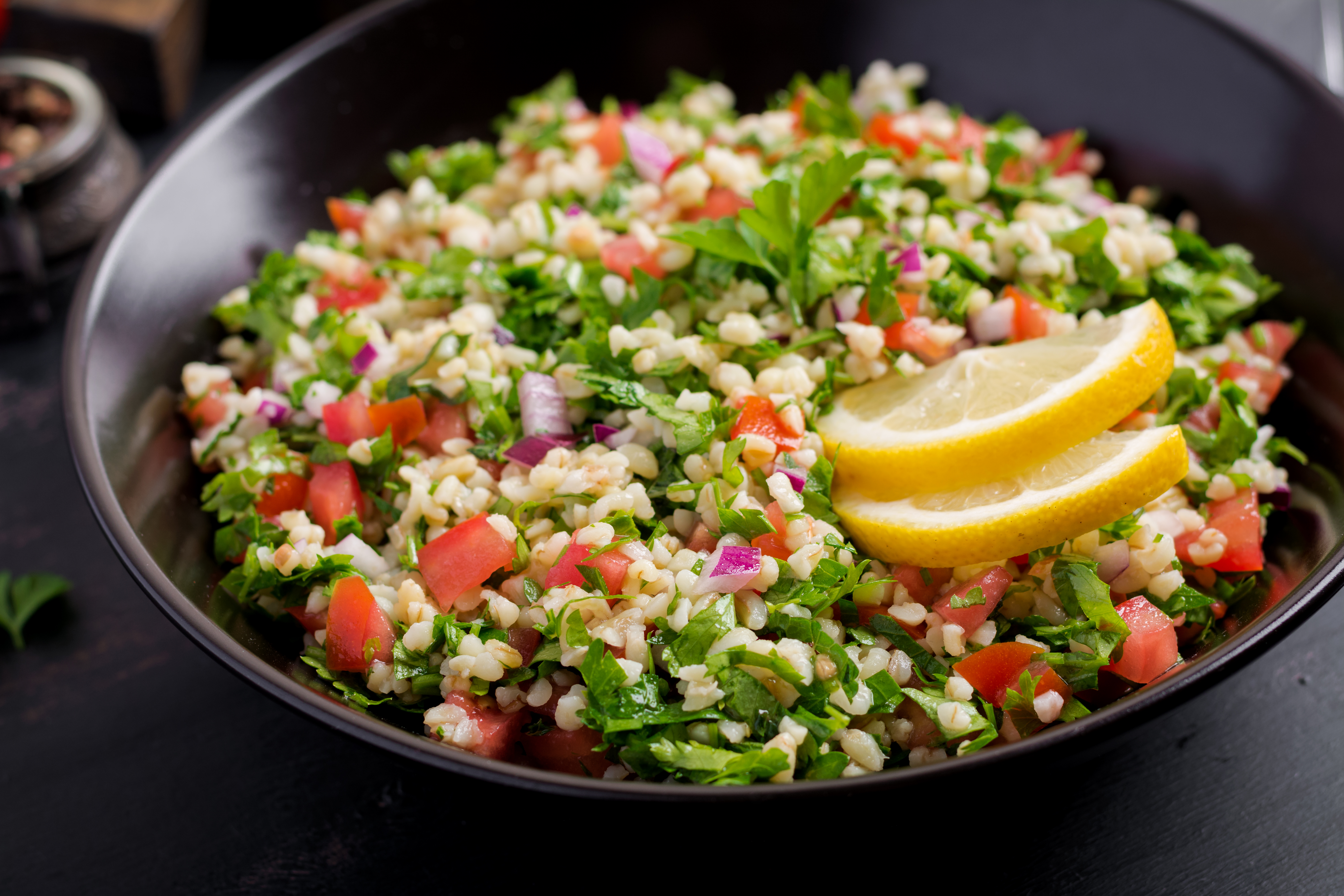 A colorful bowl of tabbouleh with lemon slices