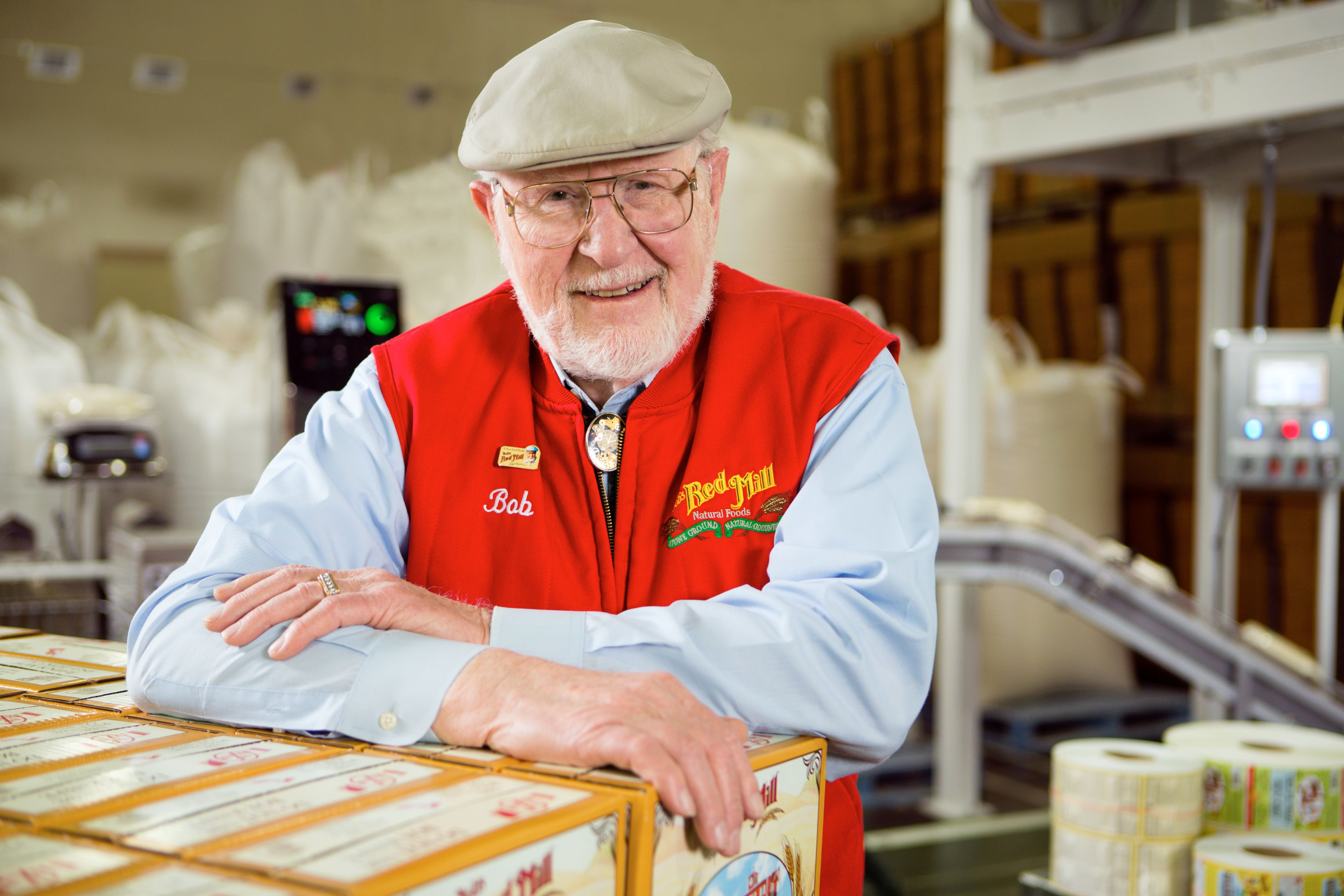 Bob Moore leaning on boxes of Bob's Red Mill products
