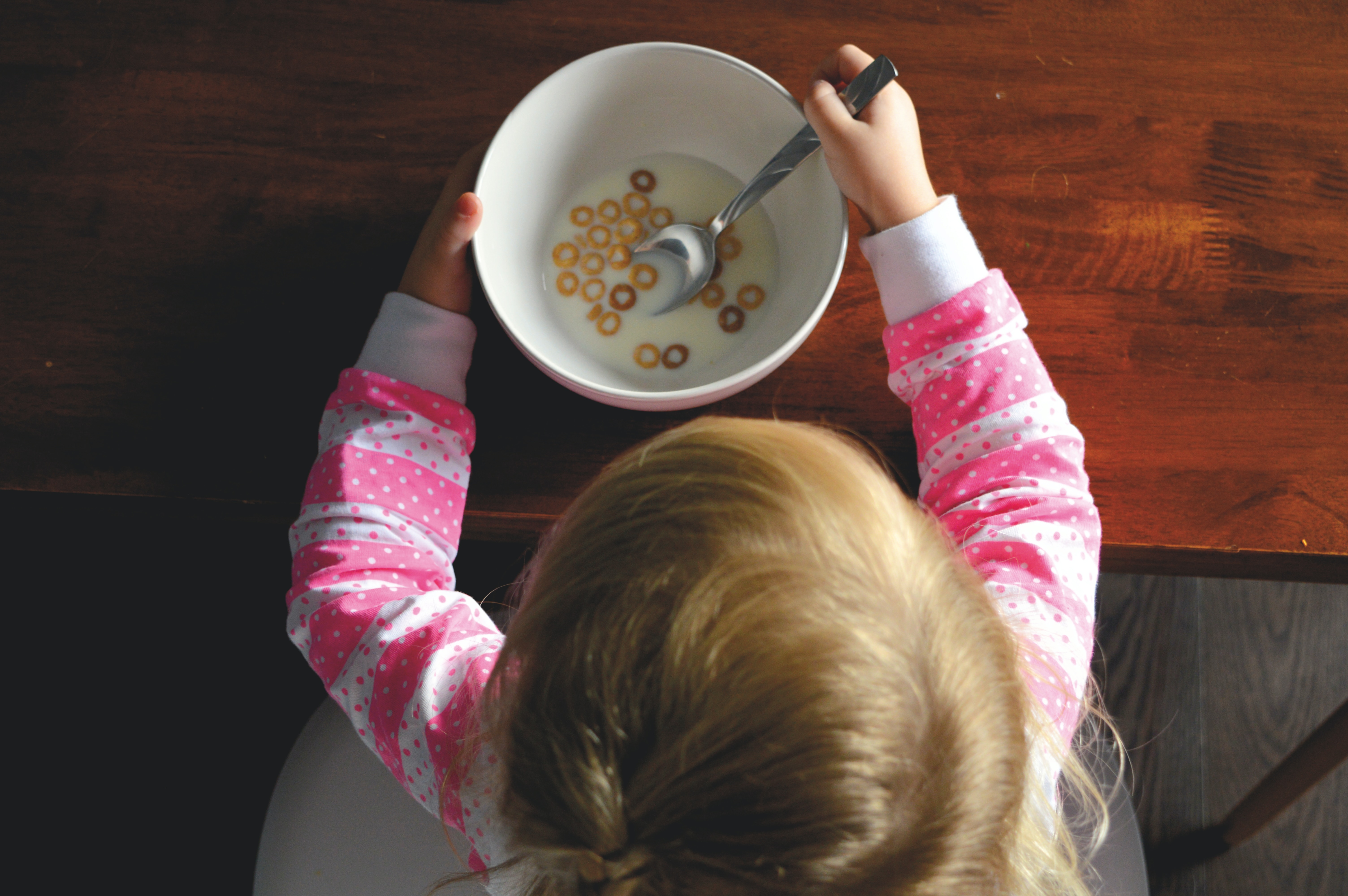 overhead view of blond toddler eating cereal
