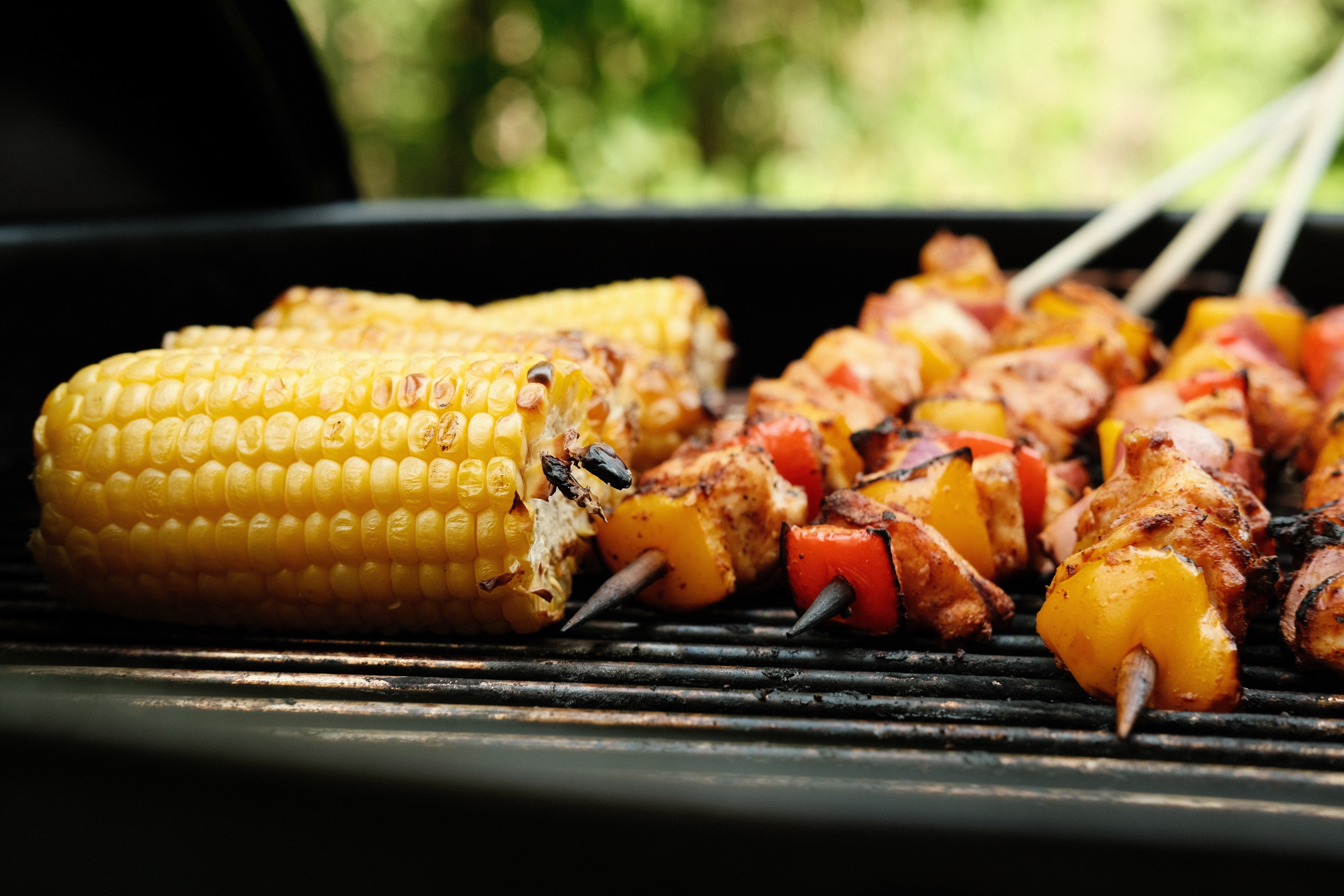 Corn and skewers of vegetables roasting on a grill
