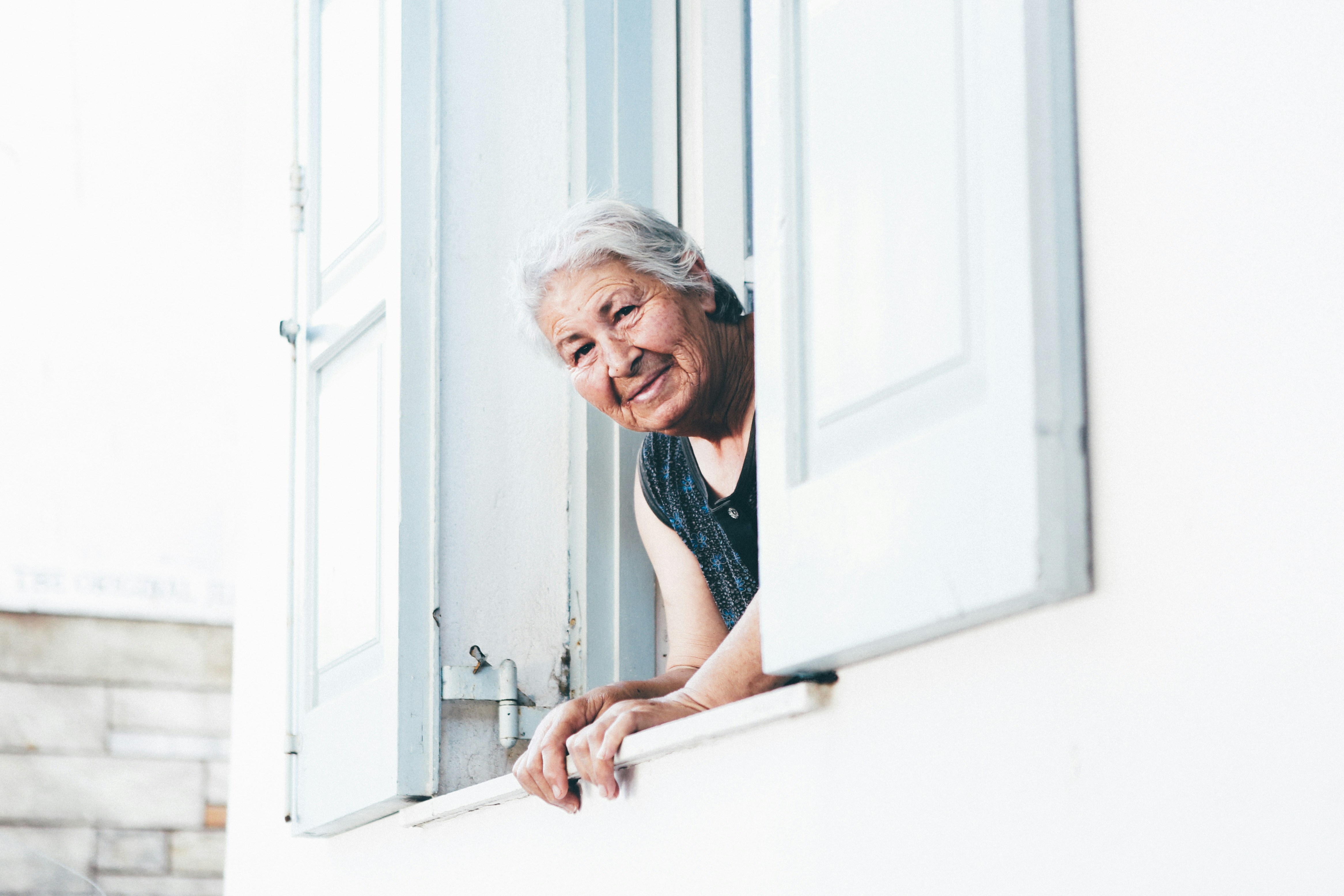 elderly woman smiling looking out a window