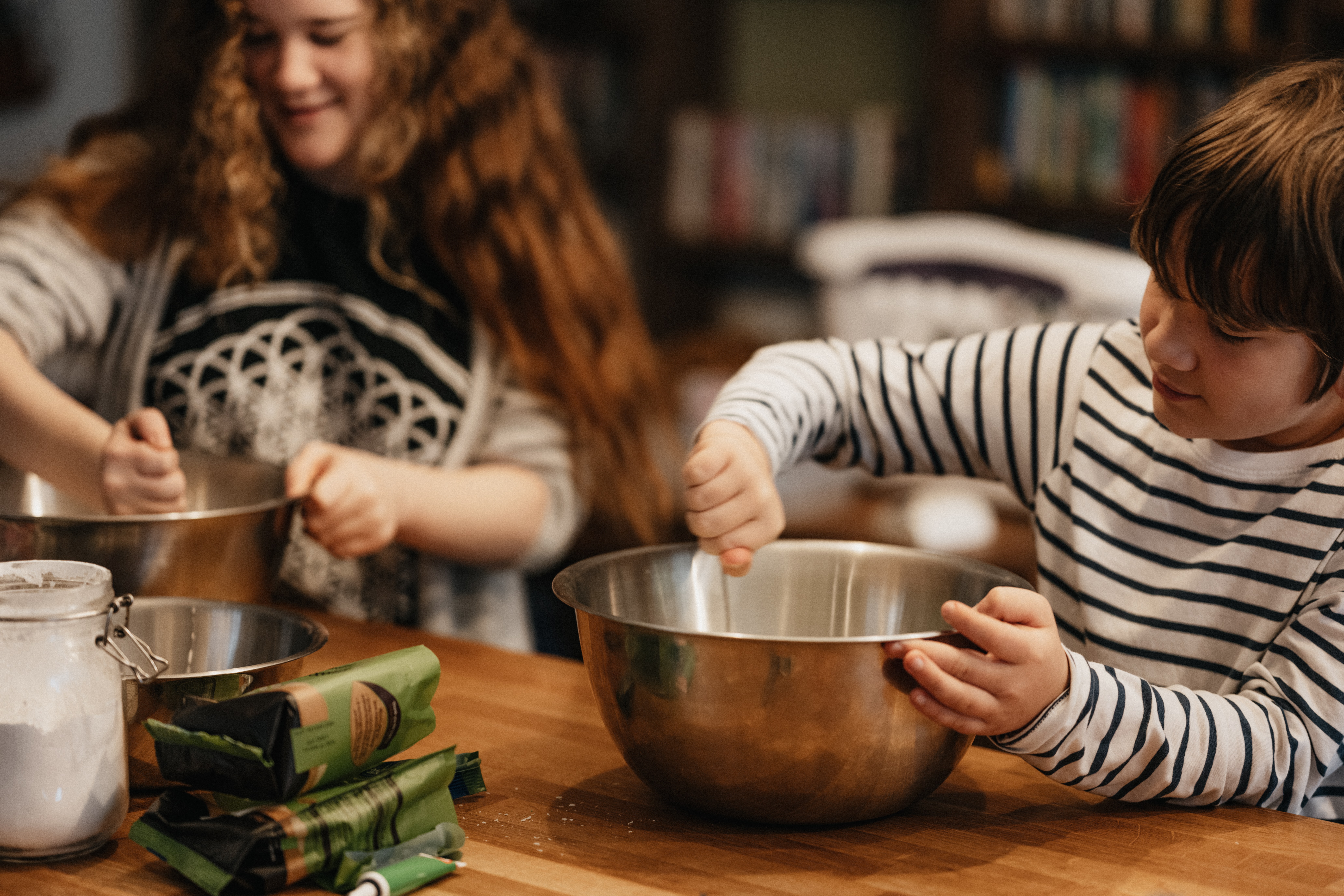 two preteen children stirring batter in mixing bowls