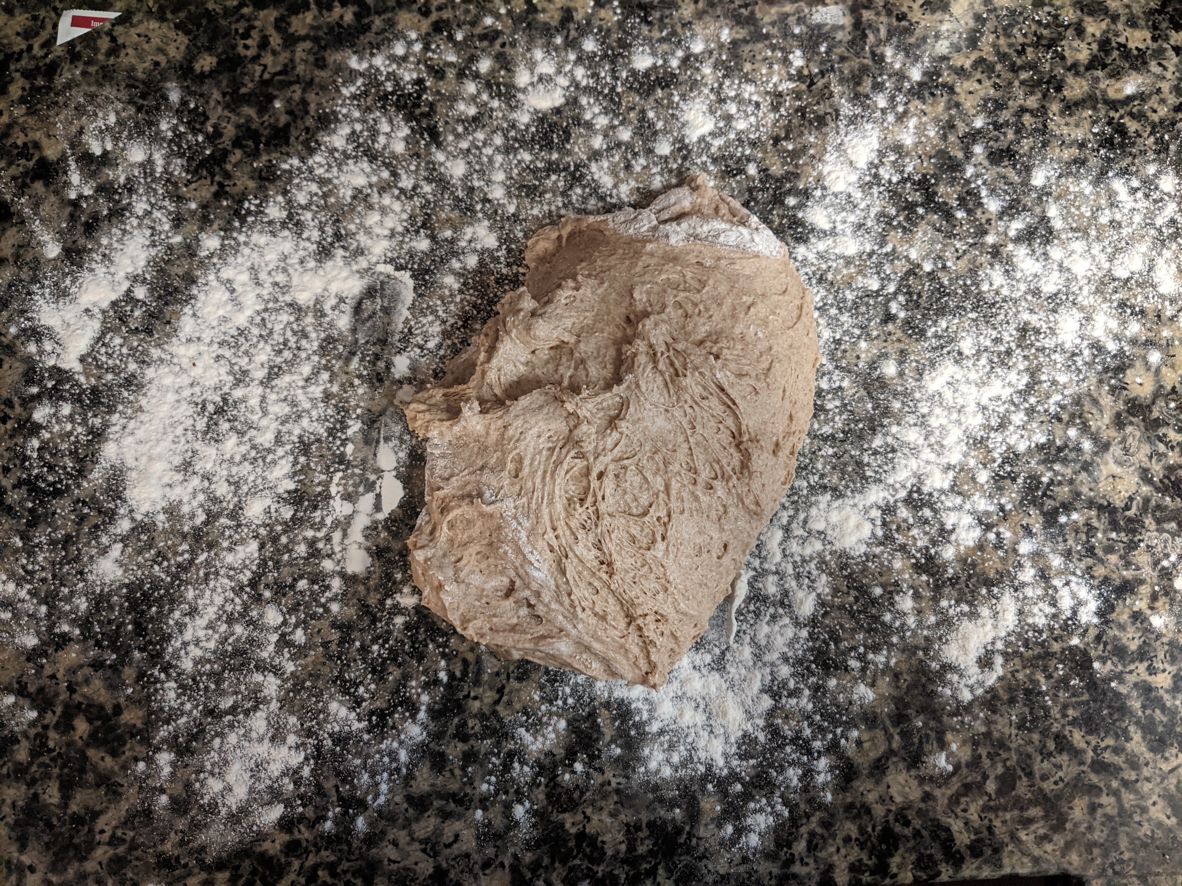 dough sitting on lightly floured dark countertop