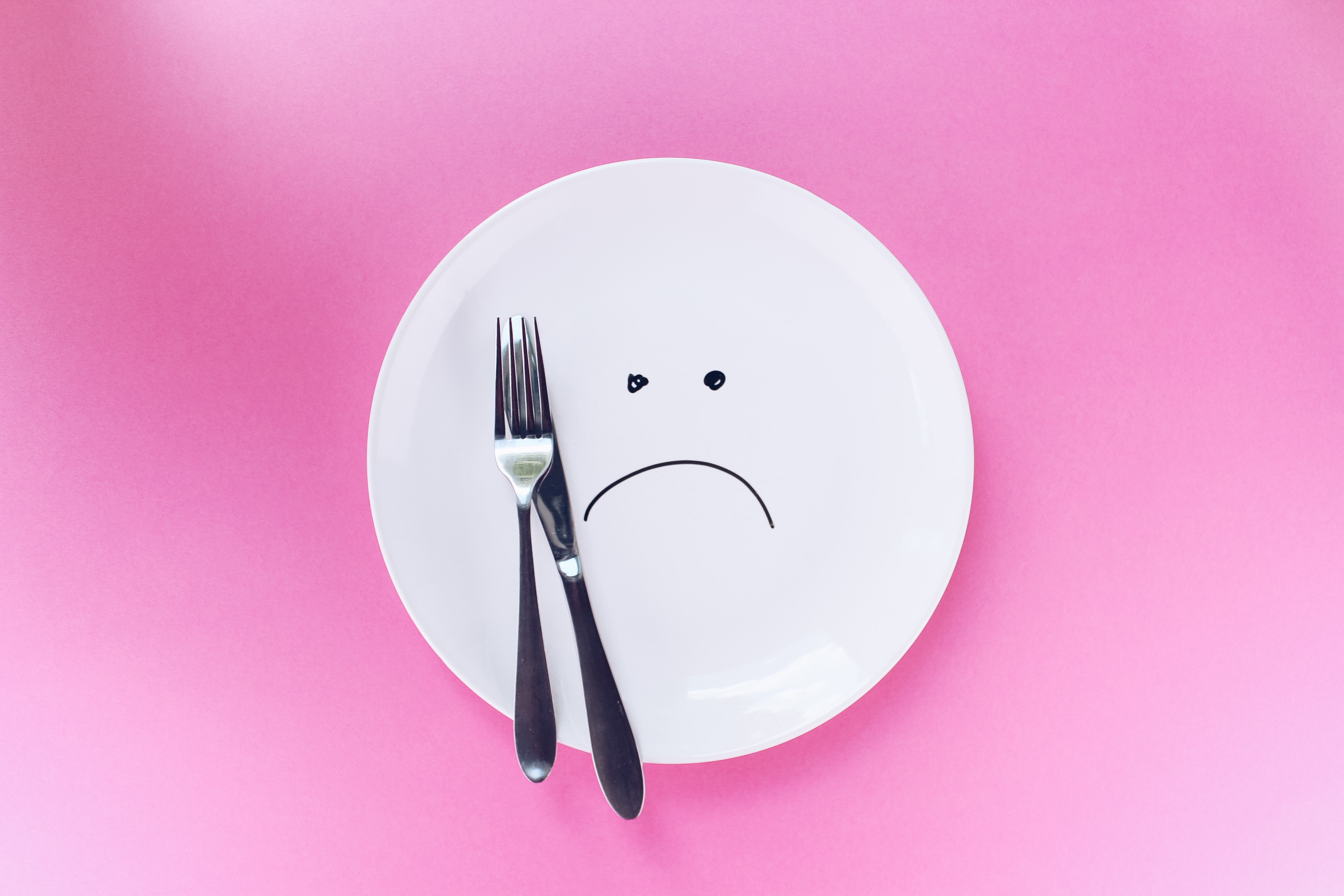 plate with frown on pink background